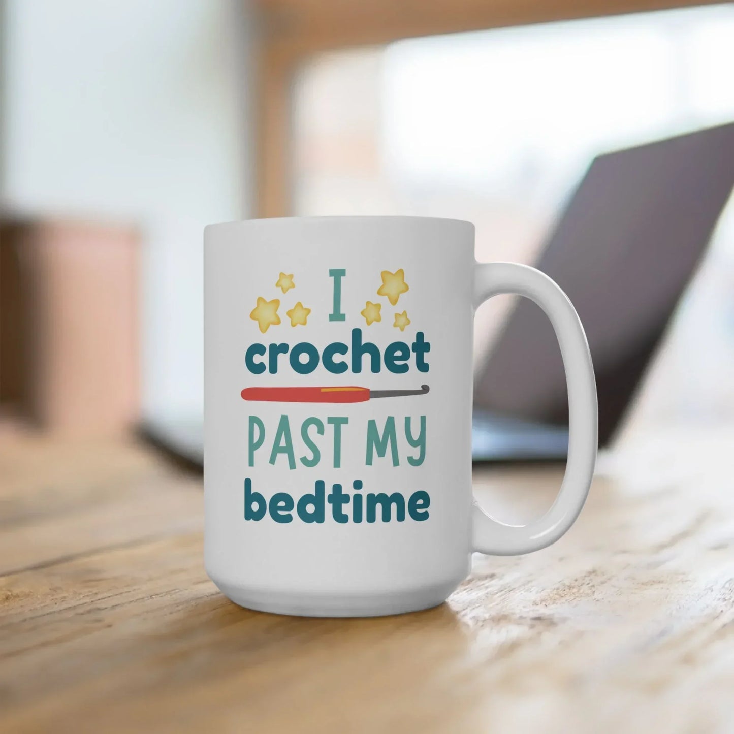 White mug with 'I crochet past my bedtime' and crochet hook design on a desk.