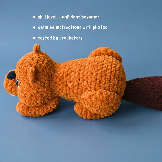 Crochet beaver plushie lying on blue surface, beginner amigurumi pattern with instructions