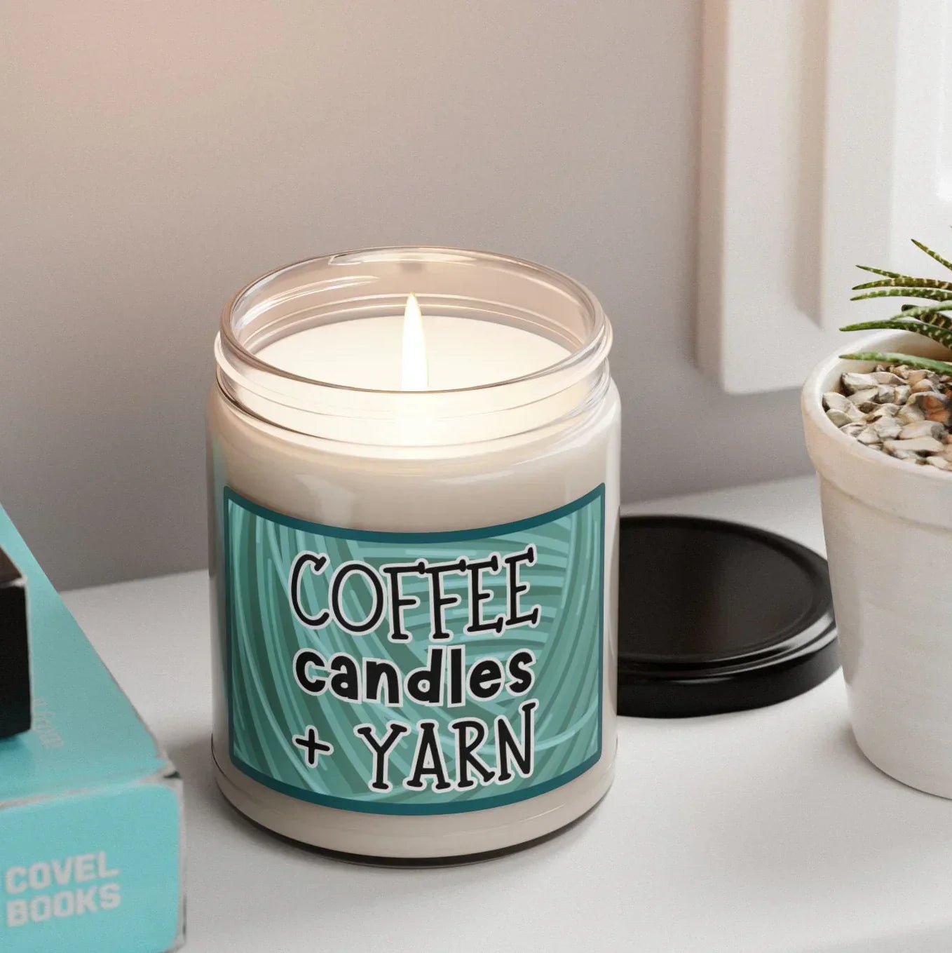 Lit coffee candles and yarn candle jar on desk with books and succulent plant