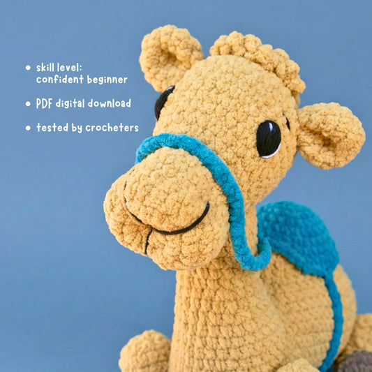 Crochet camel plushie with blue harness and saddle, beginner amigurumi pattern PDF download.