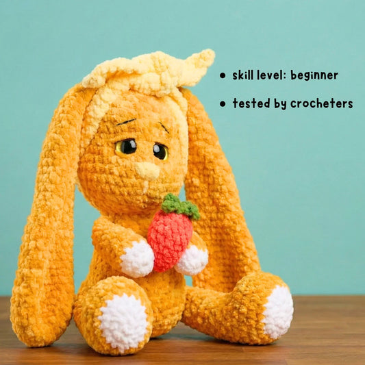 Crochet bunny plushie holding a strawberry, beginner amigurumi pattern, light teal background.