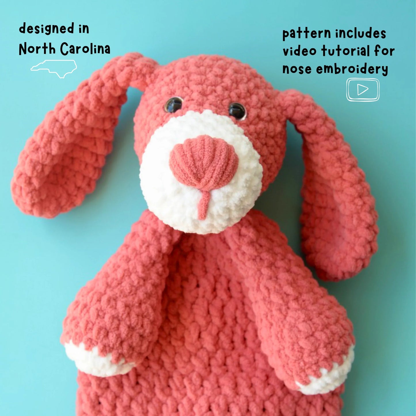 Pink crochet dog plushie with embroidered nose on blue background, amigurumi pattern.