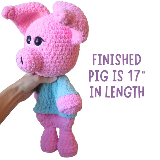 Hand holding a pink crochet pig plushie with blue sweater, 17 inches long, amigurumi toy.
