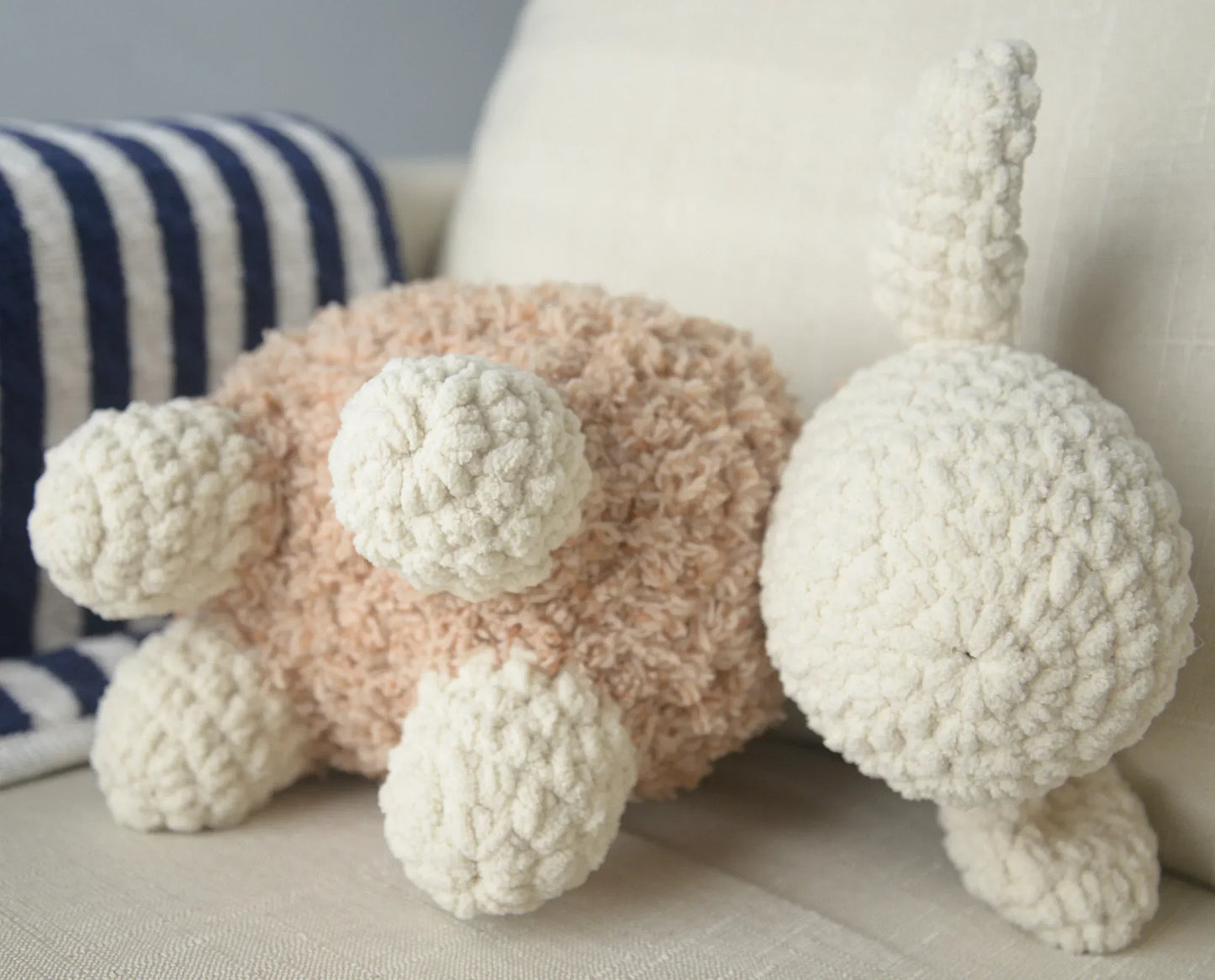 Plush crochet sheep amigurumi toy with cream and beige yarn on a beige couch