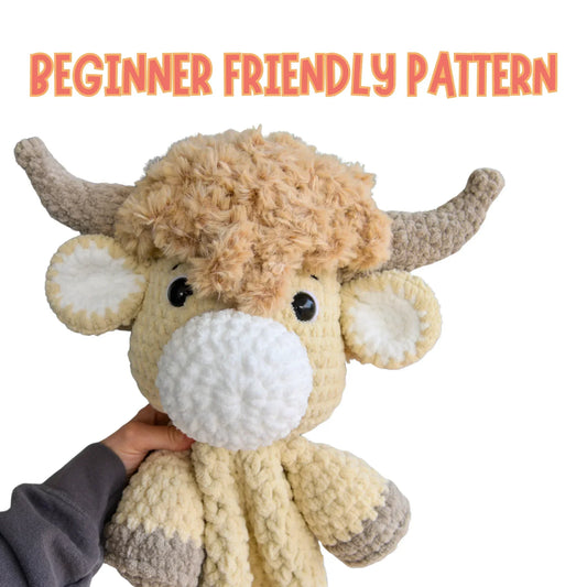 Hand holding crochet Highland cow plushie with fluffy hair, labeled beginner friendly pattern.