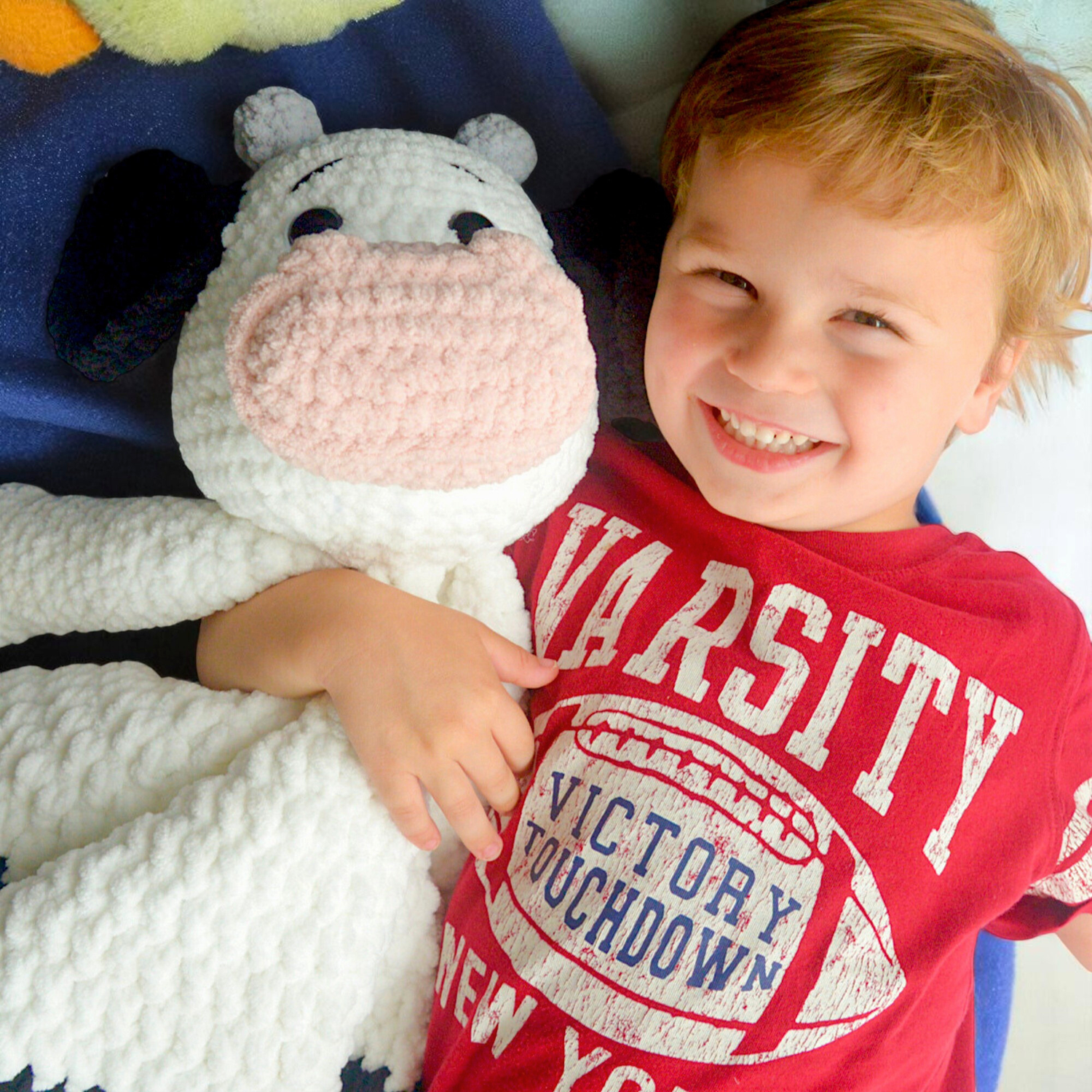 crochet cow blanket with kid hugging it