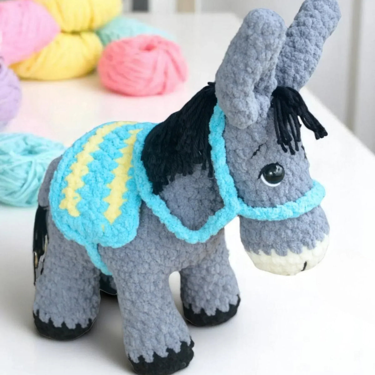 crochet donkey plush with blue and yellow blanket, amigurumi pattern, yarn in background