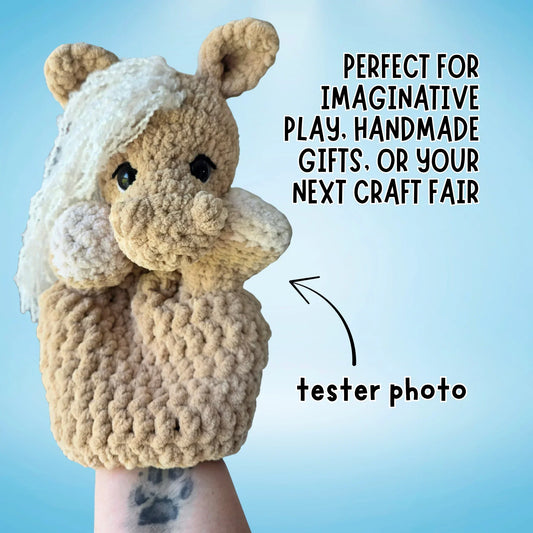 Crochet horse hand puppet with a cream mane, displayed on a hand against a blue background.
