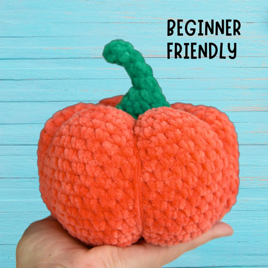 Hand holding a plush crochet pumpkin with green stem, beginner-friendly amigurumi pattern