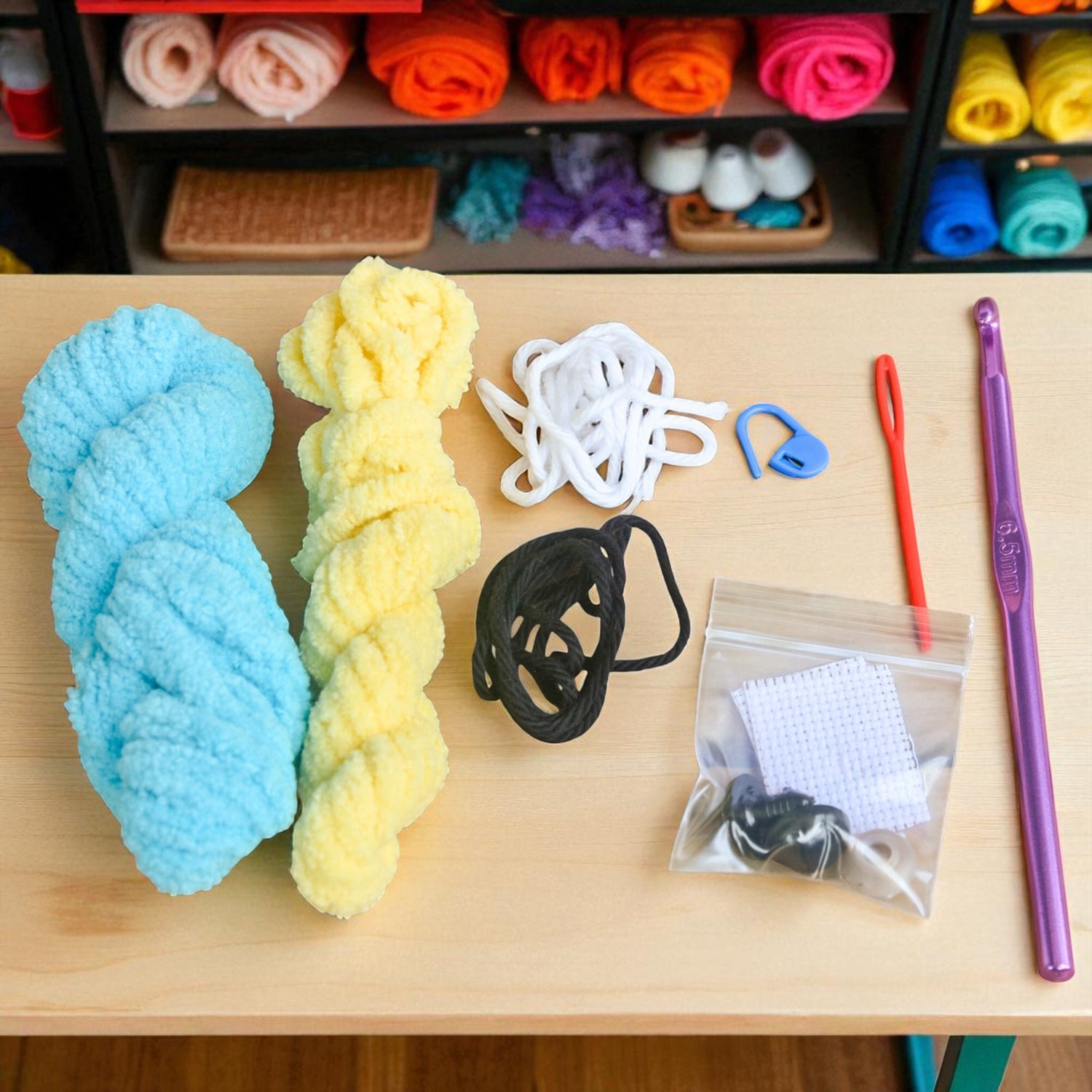 Colorful yarn skeins and crochet hooks on a wooden table with a shelf of yarn in the background.