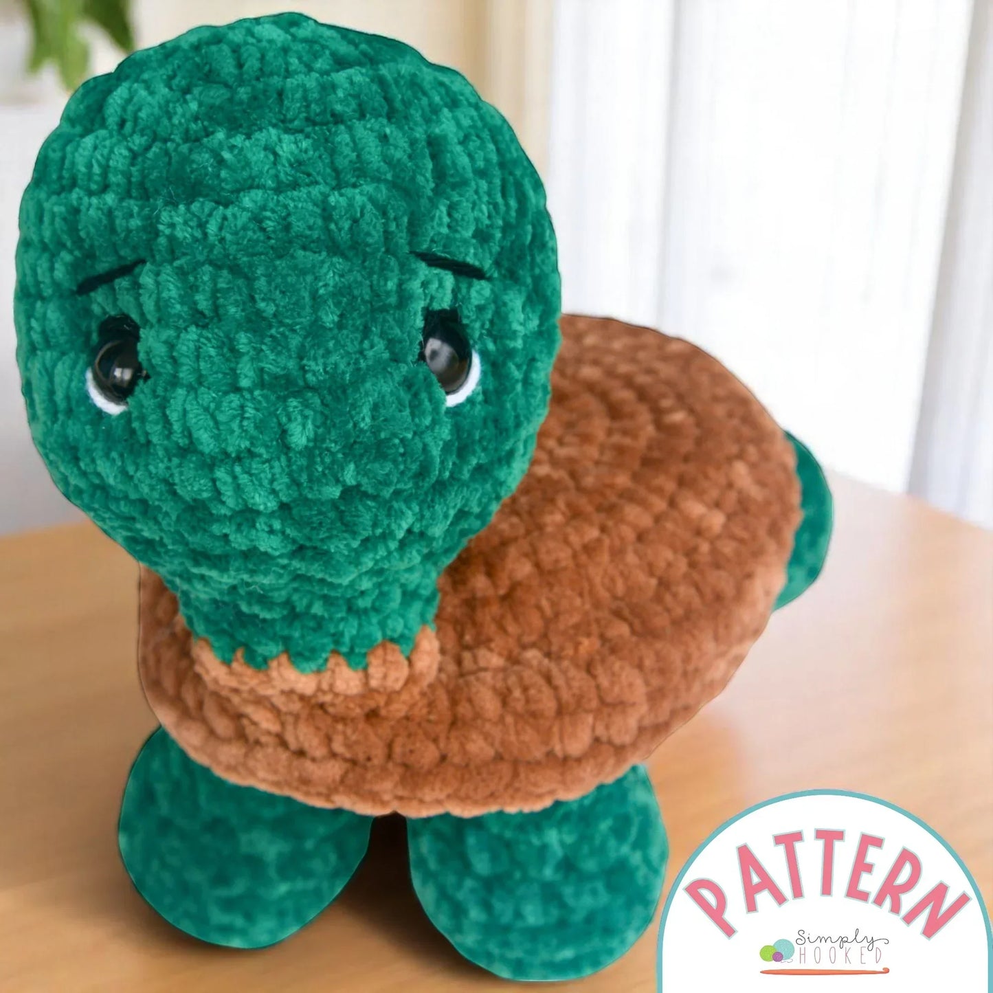Green and brown crochet turtle plushie amigurumi toy on a wooden table