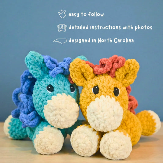 Two plush crochet horse amigurumi toys with colorful manes on a wooden surface