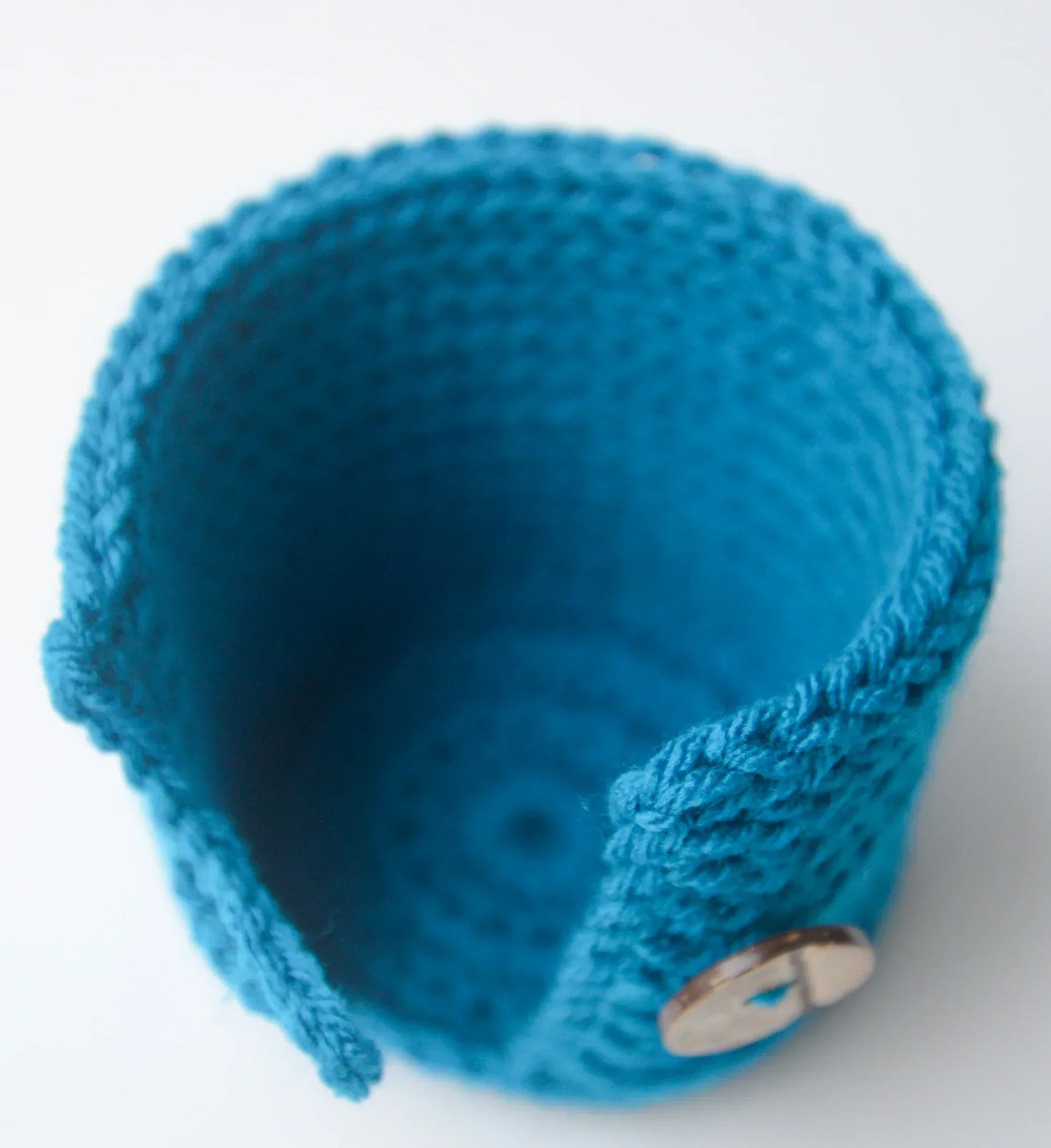 Blue crocheted cozy with button, handmade yarn accessory on white background