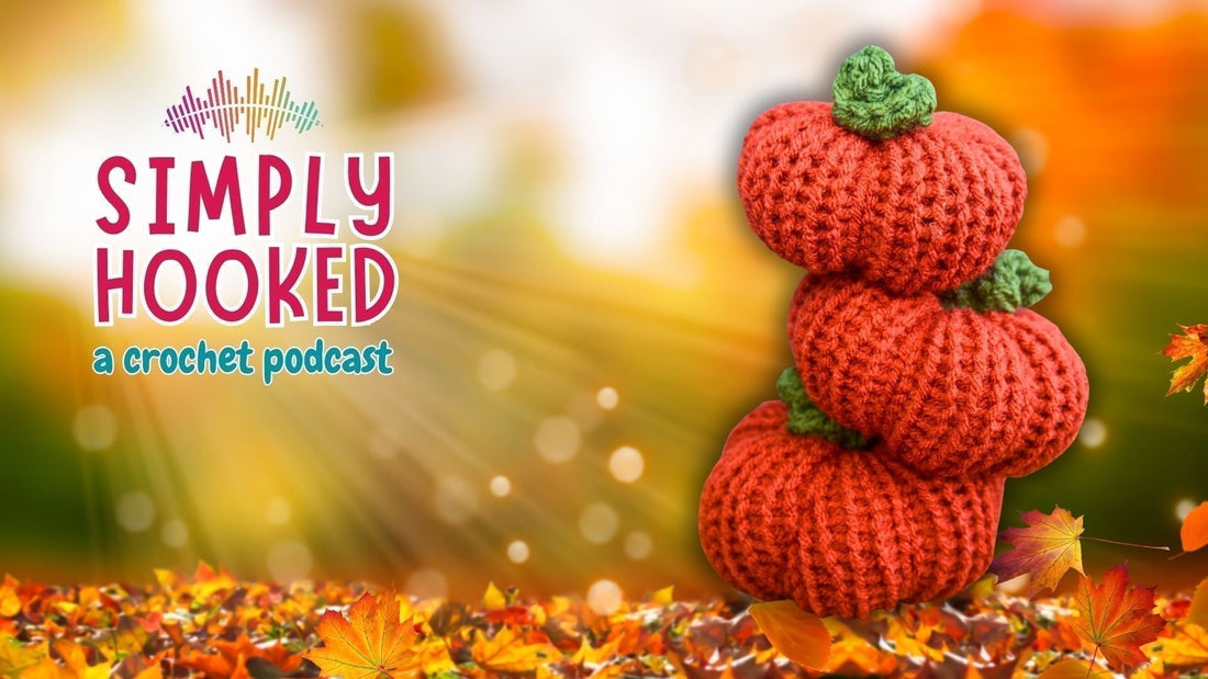 Stack of three crocheted orange pumpkins with green stems on autumn leaves background