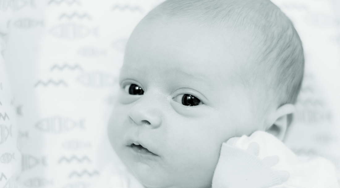 Close-up of a newborn baby lying on patterned fish and waves blanket