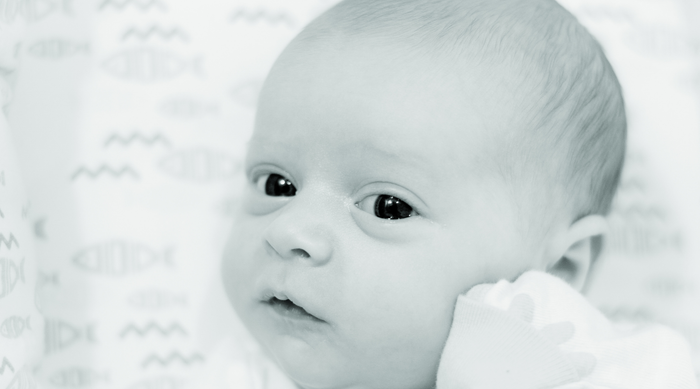 Close-up of a newborn baby lying on patterned fish and waves blanket