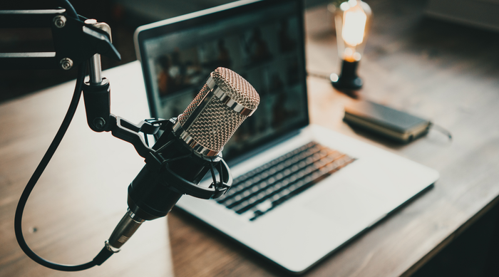 Close-up of professional studio microphone on desk with laptop and warm light bulb