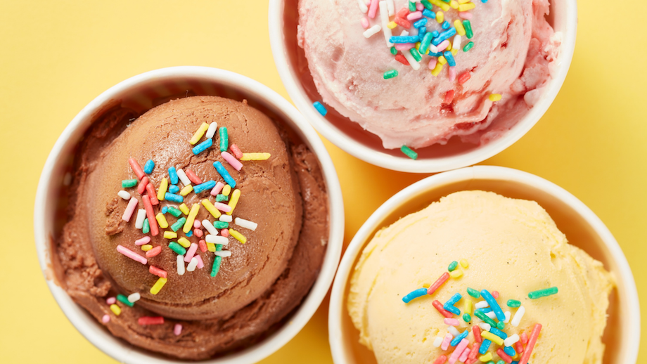 Three bowls of chocolate, strawberry, and vanilla ice cream with rainbow sprinkles on yellow background.