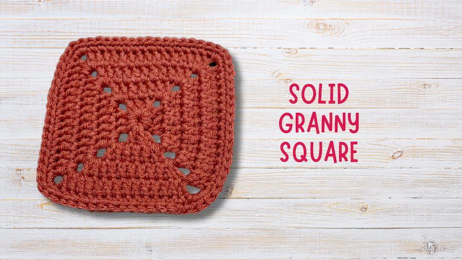 Crochet solid granny square in rust yarn on white wood background, text reading solid granny square.