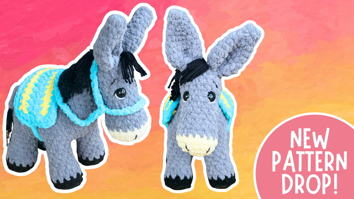 Two grey crocheted donkey plush toys with black manes and blue yellow saddle blankets on a pink and orange background