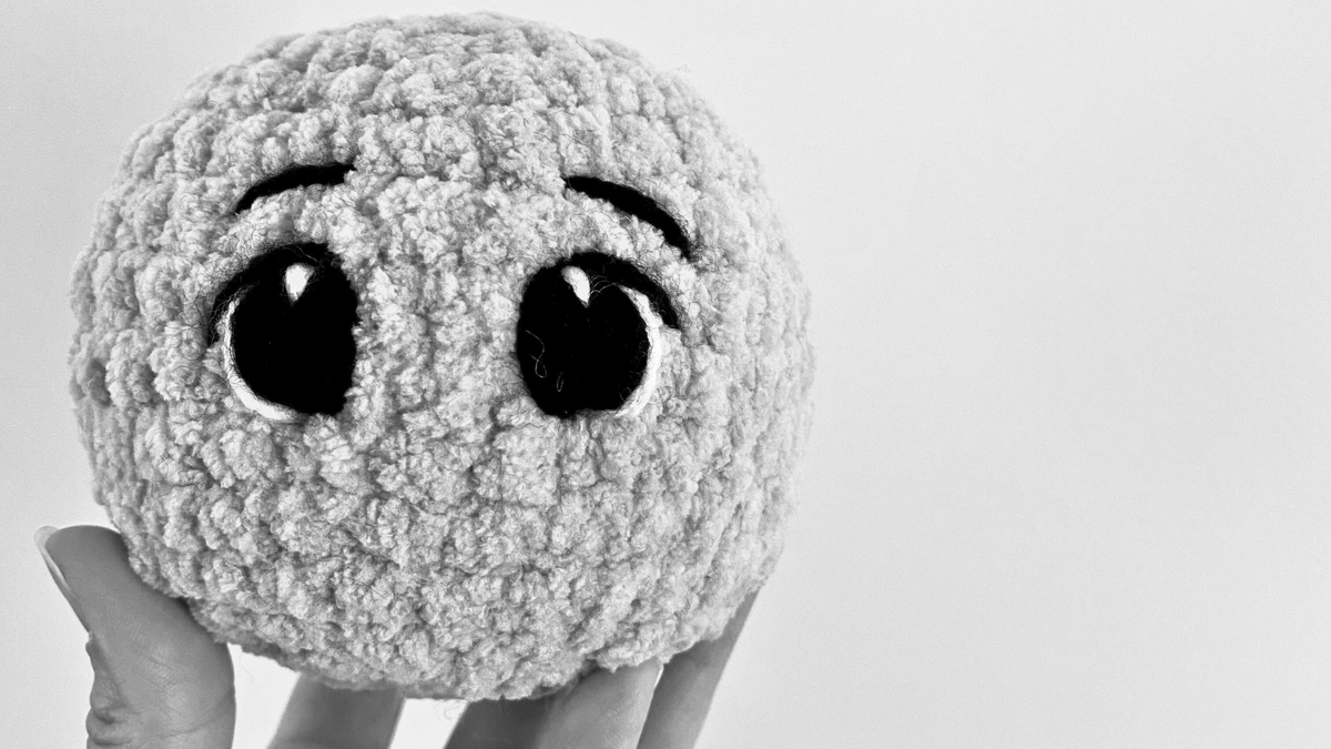 Hand holding a beginner-friendly crochet amigurumi plushie with big eyes