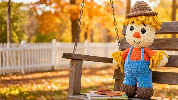 Crochet scarecrow plushie amigurumi on a wooden swing in autumn outdoor setting