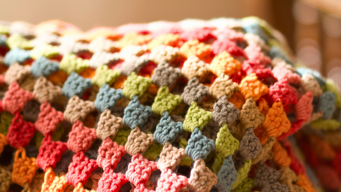 Colorful granny square crochet blanket with warm lighting and textured yarn