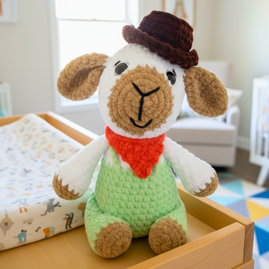 Crocheted plush lamb with brown hat, red scarf, and green outfit sitting on wooden changing table