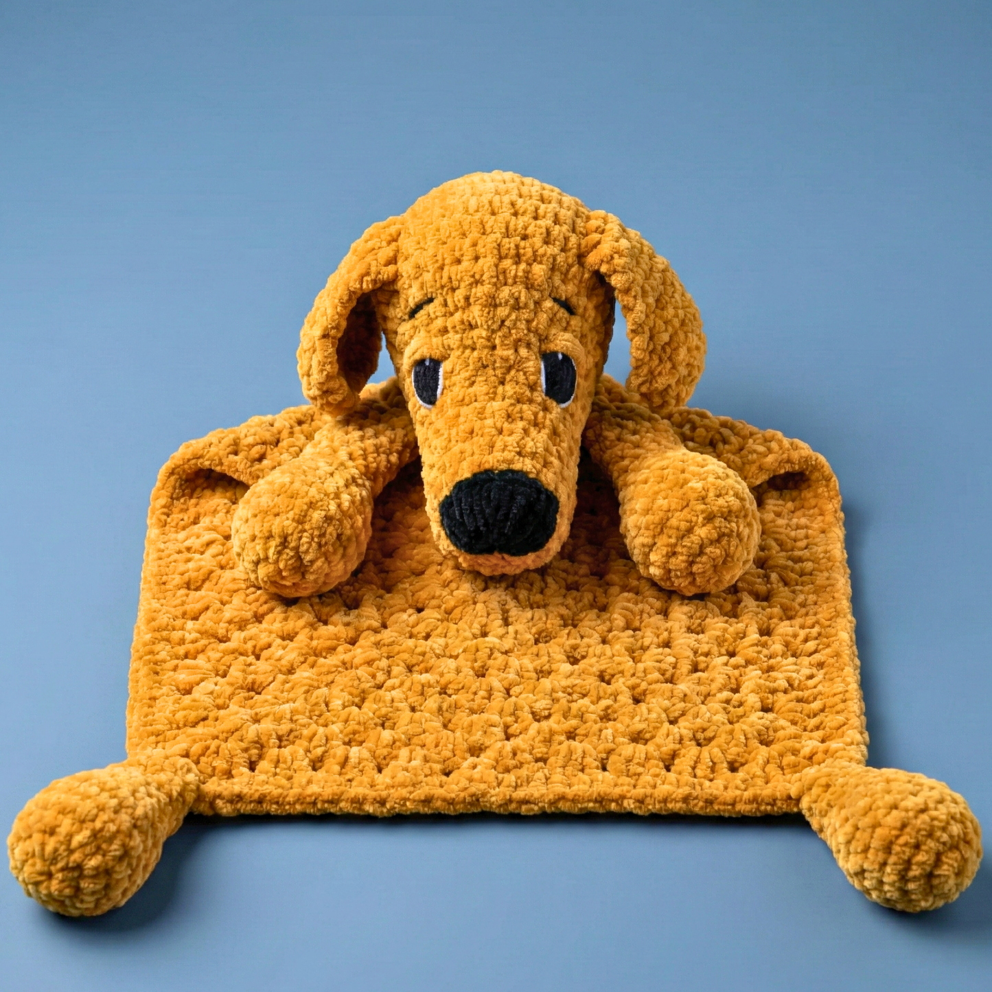 Plush yellow dog-shaped cuddle blanket with textured fabric on blue background