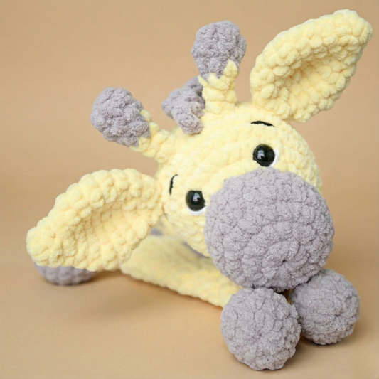 Soft handmade crochet giraffe plush toy in yellow and gray on beige background