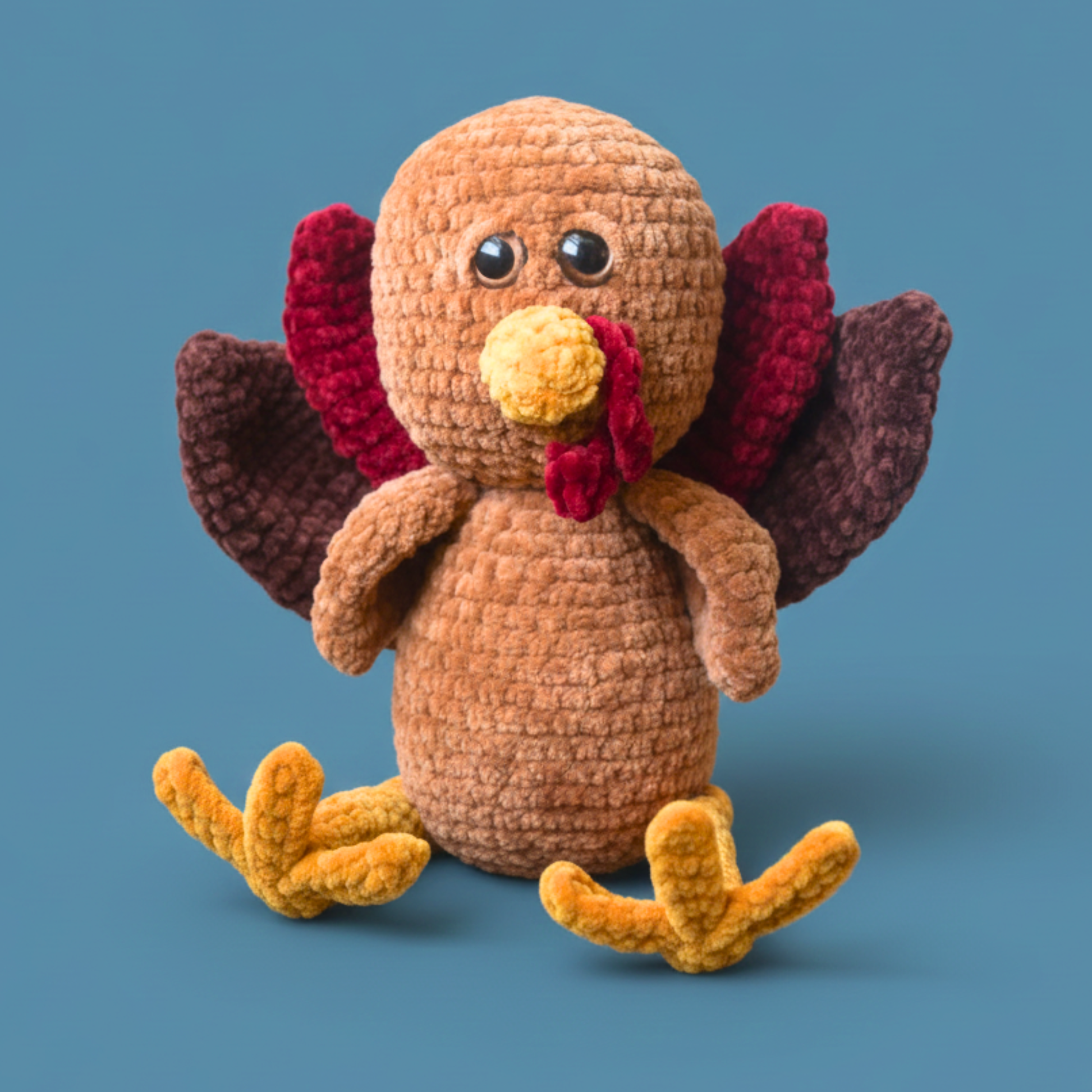 Handmade crochet turkey plush toy with brown, red, and yellow yarn on blue background