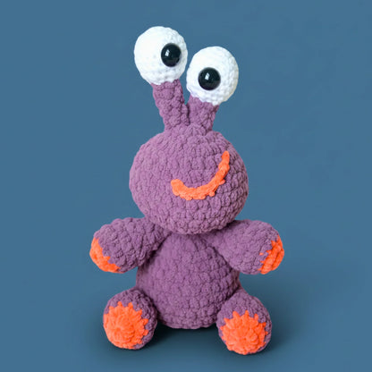 Purple crochet plushie with large eyes and orange accents, beginner amigurumi stuffed animal