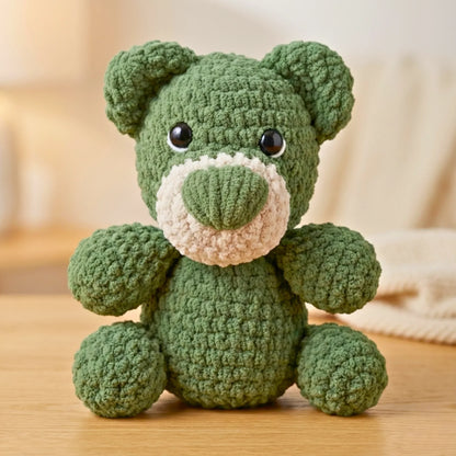 Green crochet teddy bear plushie with big eyes, sitting on a wooden surface