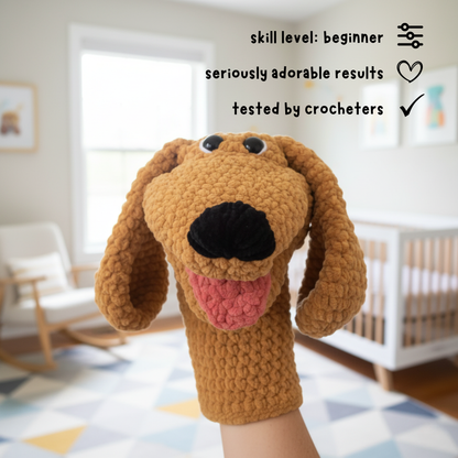 Hand holding a crocheted brown dog puppet in a modern nursery with crib and rocking chair