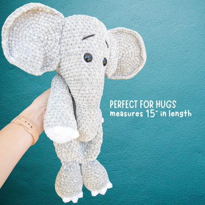 Hand holding a crocheted gray elephant plush toy against a teal textured background with text about size and comfort