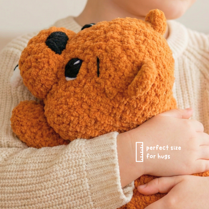 Child in cream sweater hugging soft orange plush bear toy, perfect size for hugs
