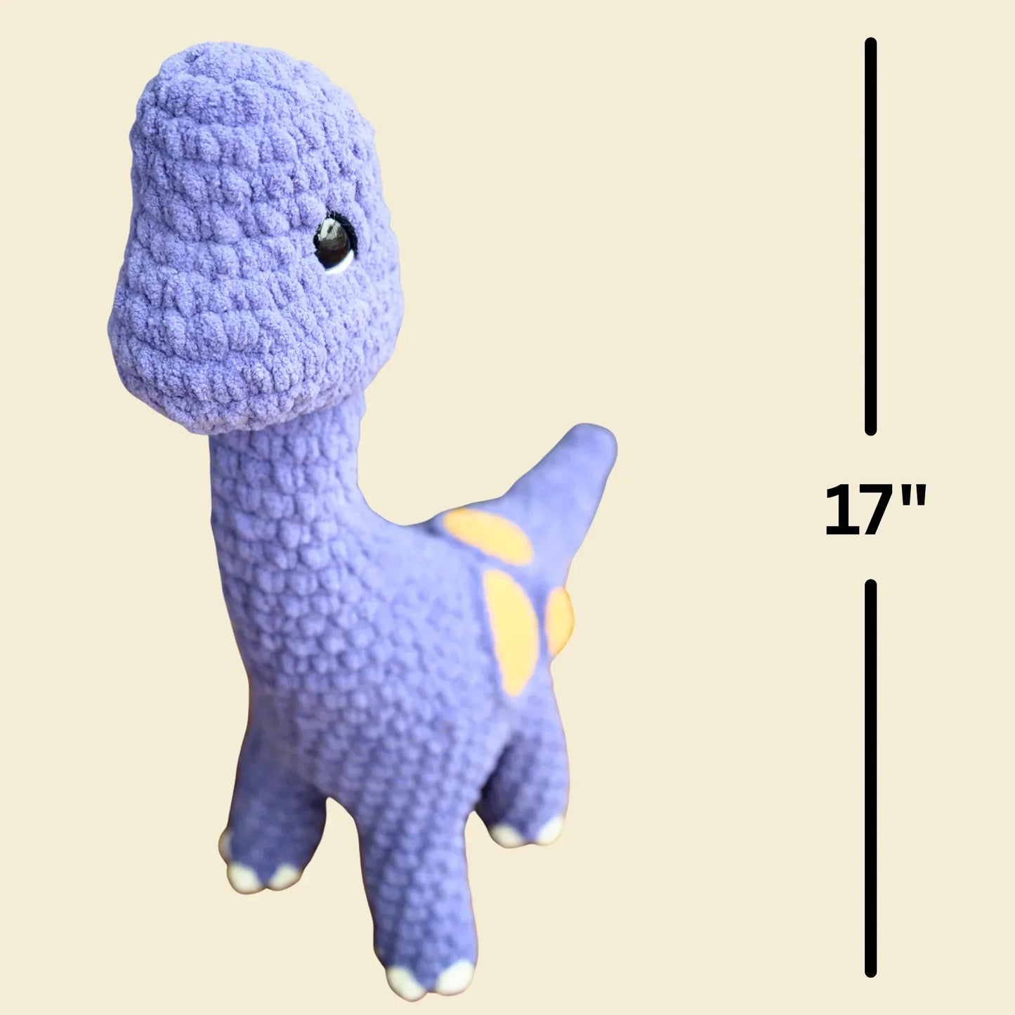 Purple crochet brontosaurus plushie with yellow spots, 17 inches tall, on beige background.