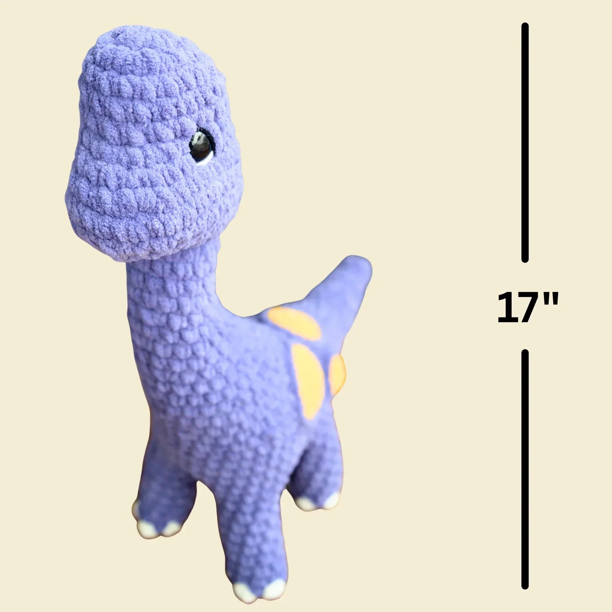 Purple crochet brontosaurus plushie with yellow spots, 17 inches tall, on beige background.