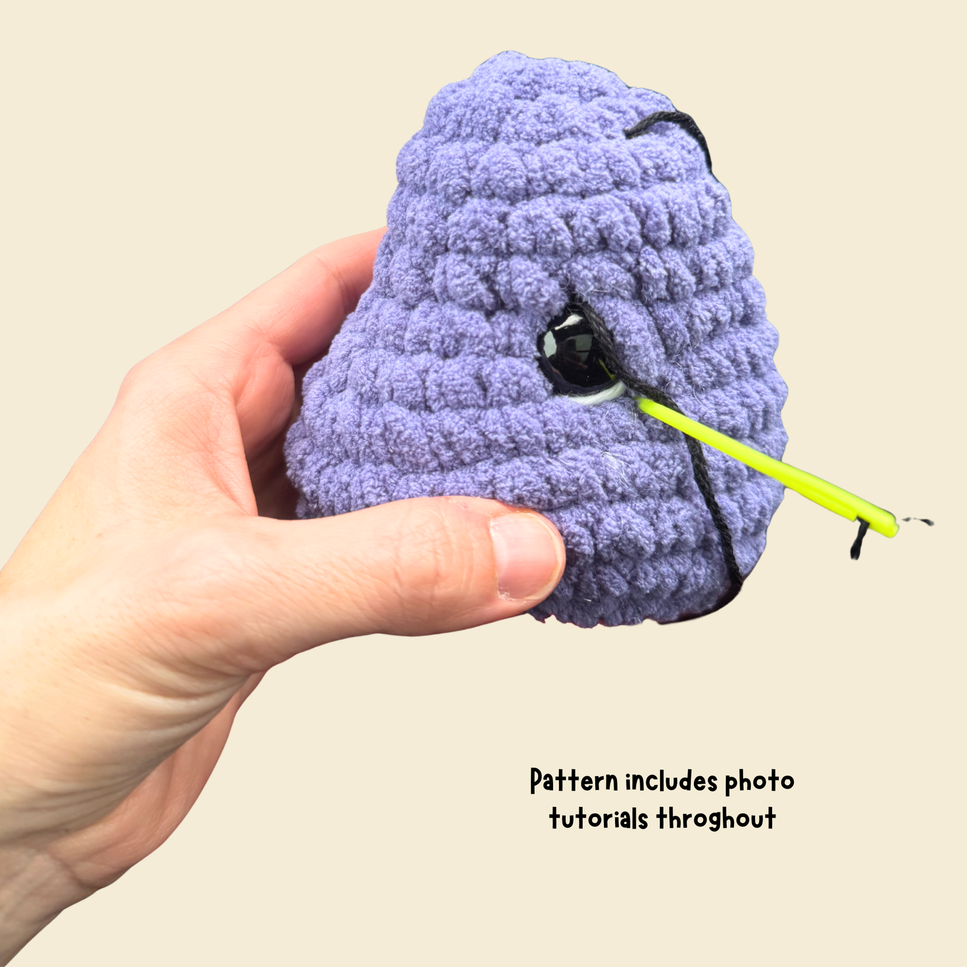 Hand holding a purple textured object with a yellow tool on a beige background