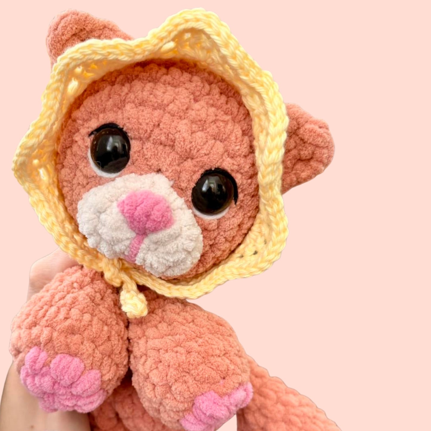Pink plush toy with a yellow hat on a pink background