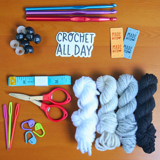 Crochet supplies including yarn, hooks, scissors, and a 'Made with Love' tag on a wooden surface.