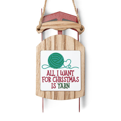 Wooden sled ornament with a sign saying 'All I want for Christmas is yarn' on a white background