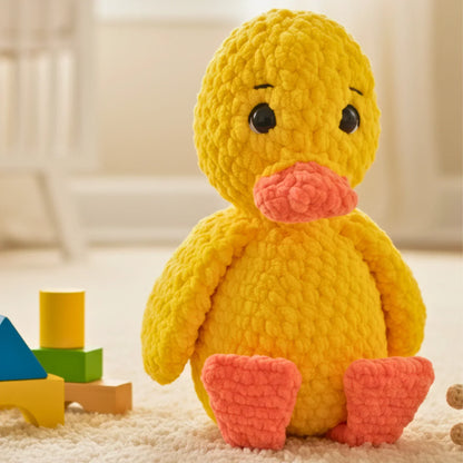 Plush yellow crochet duck amigurumi with orange beak and feet, sitting on a soft carpet.