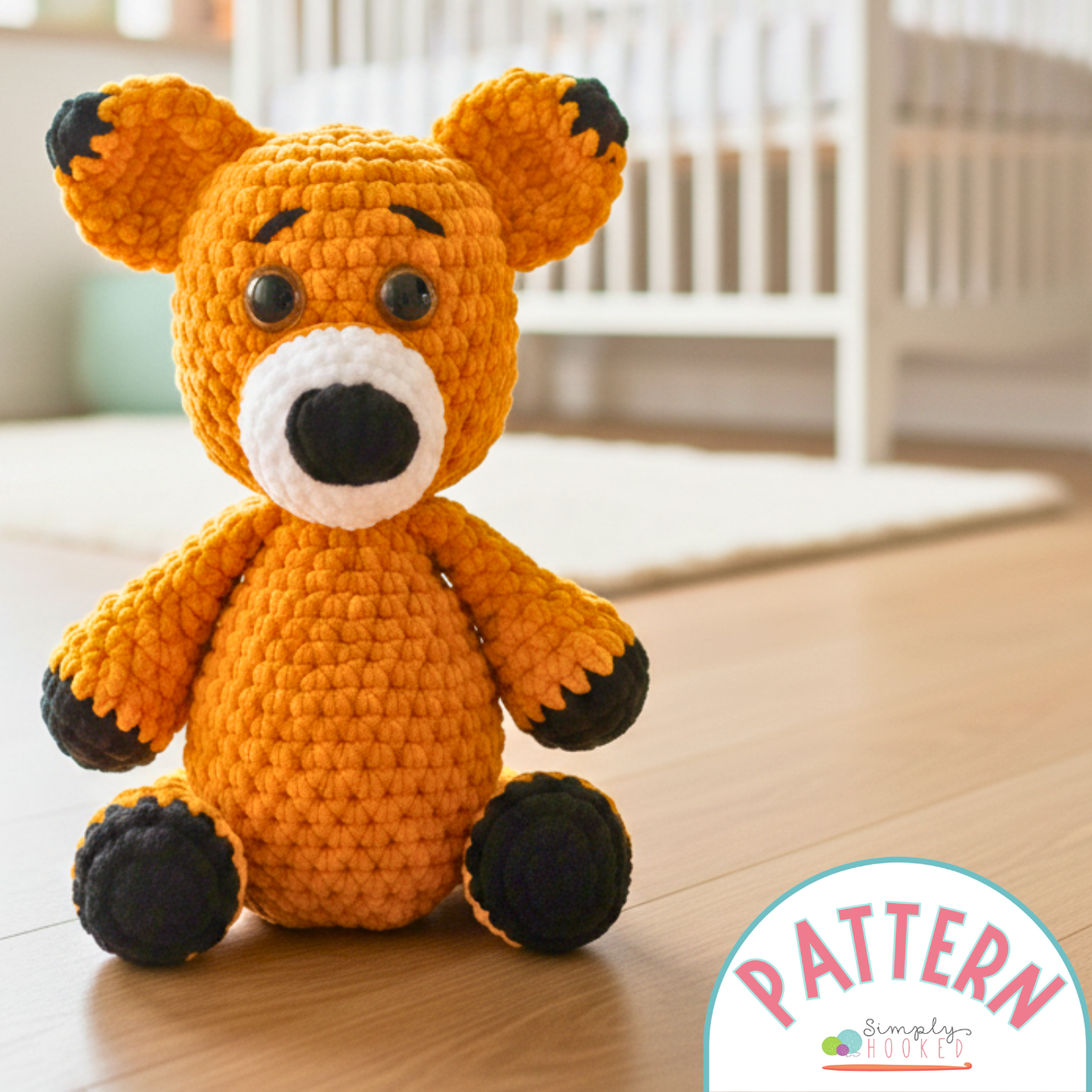 Crocheted fox toy on a wooden floor with 'Simply Hooked' pattern label.