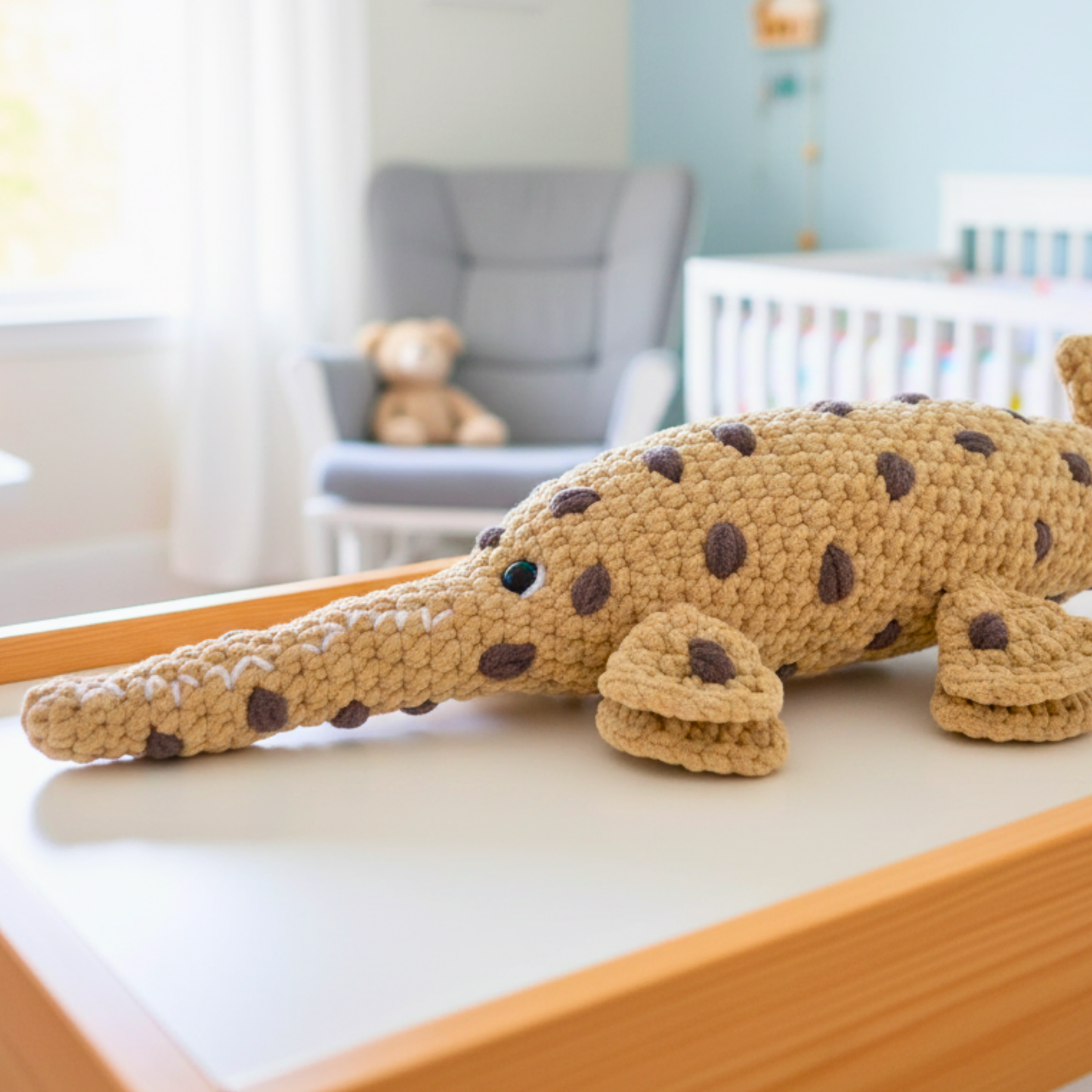 Crocheted plush alligator toy on a wooden changing table in a pastel nursery