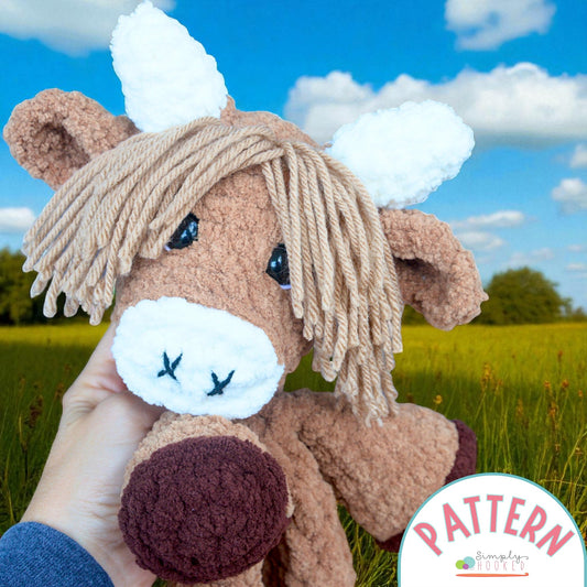 Hand holding a plush toy cow with a pattern logo in the corner