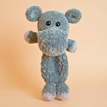 Plush crochet hippo stuffed animal with big eyes, made from soft yarn, on a beige background