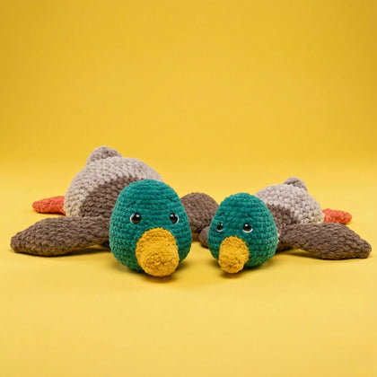 Plush crochet mallard ducks amigurumi with green heads and yellow beaks on yellow background.