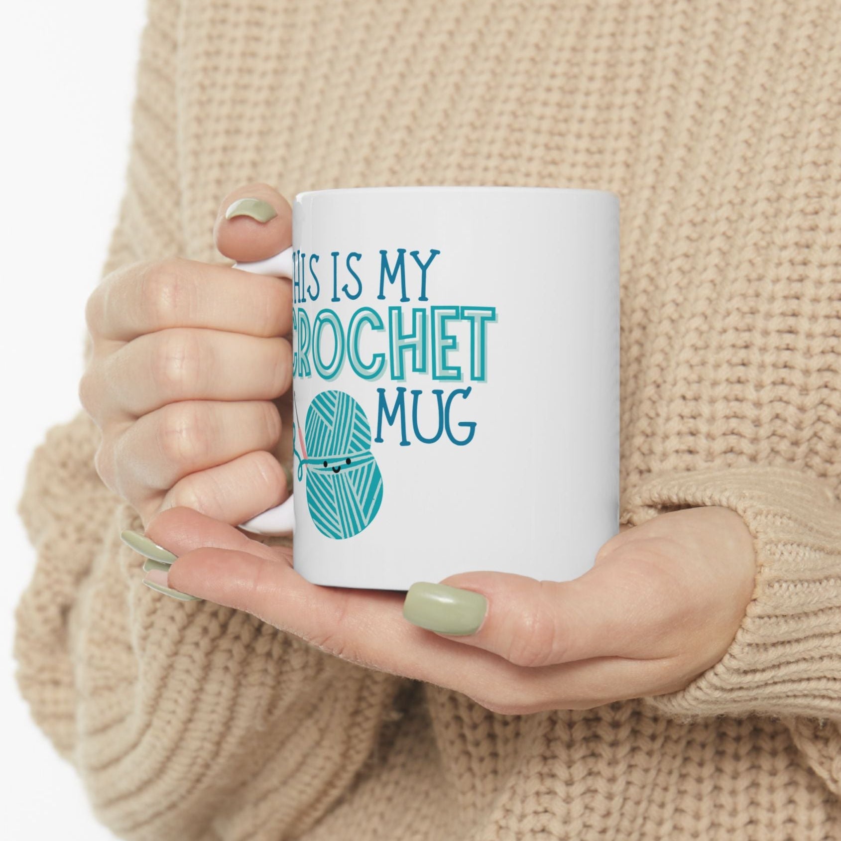Person holding a white mug with 'This is my crochet mug' text and yarn ball design.