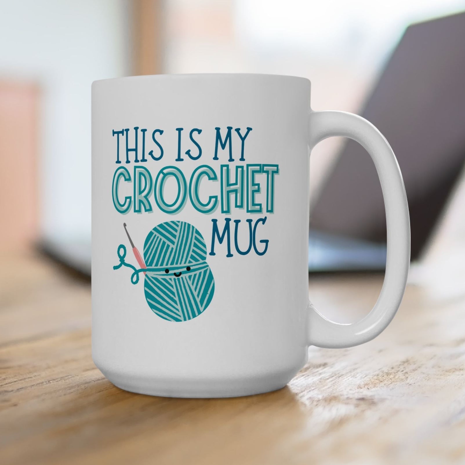White mug with 'This is my crochet mug' text and yarn graphic on a wooden surface.